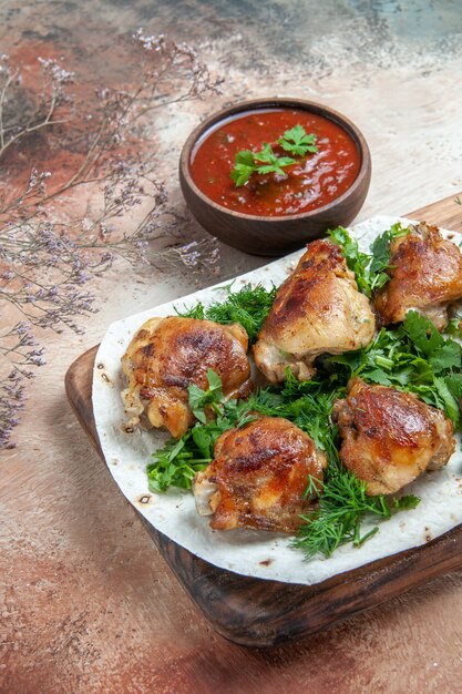 Vue latérale du poulet au poulet aux herbes sur lavash à côté du bol de sauce