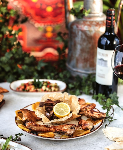 Photo gratuite vue latérale du poulet rôti servi avec du vin sur la table