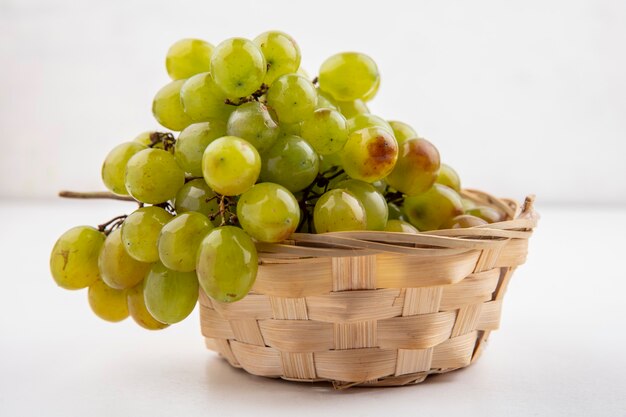 Vue latérale du raisin blanc dans le panier sur fond blanc