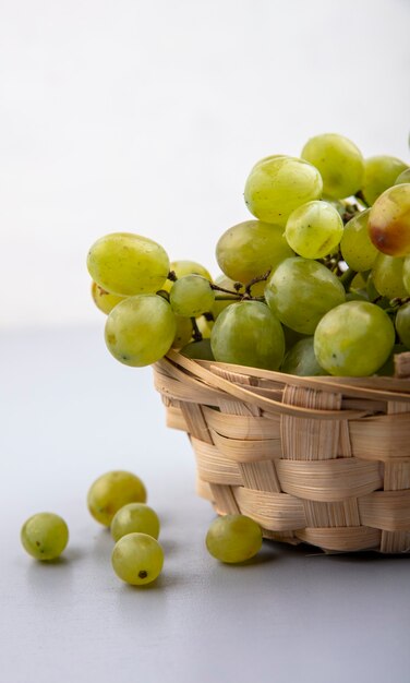 Vue latérale du raisin blanc dans le panier sur la surface grise et fond blanc