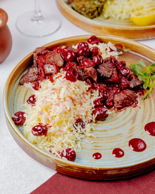 Vue latérale du riz bouilli avec de la viande et des cerises