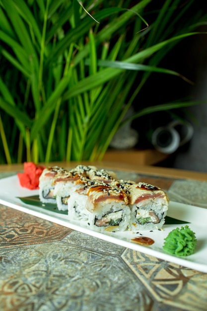 Photo gratuite vue latérale du rouleau de sushi cuisine japonaise traditionnelle avec anguille avocat et fromage à la crème sur vert