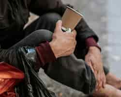 Photo gratuite vue latérale du sans-abri tenant la tasse