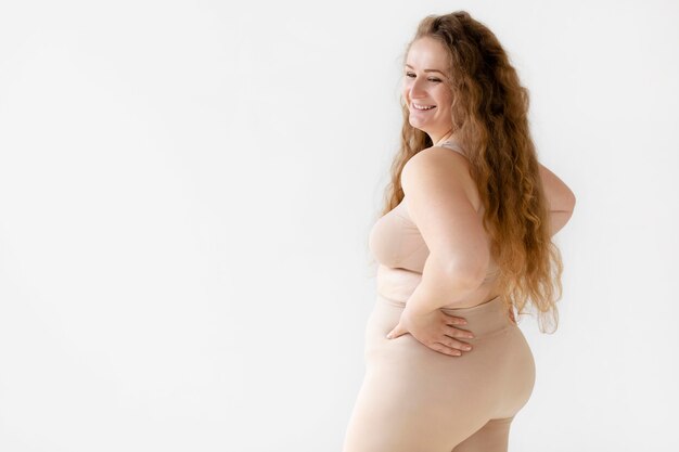 Vue latérale du smiley femme confiante posant tout en portant un body shaper