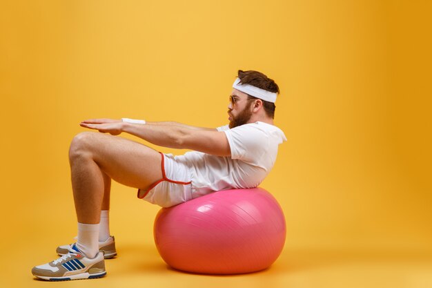 Vue latérale du sportif secoue la presse sur le ballon de fitness