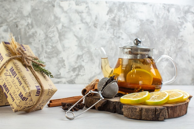 Vue latérale du thé noir cadeau avec citron et limes à la cannelle sur un plateau en bois sur une table blanche