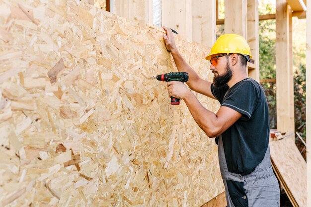 Vue latérale du travailleur de la construction de forage en contreplaqué avec copie espace