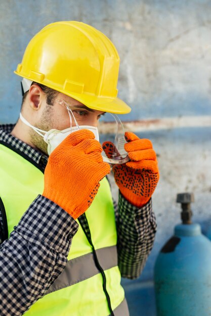 Vue latérale du travailleur masculin avec des lunettes de protection et un gilet réfléchissant