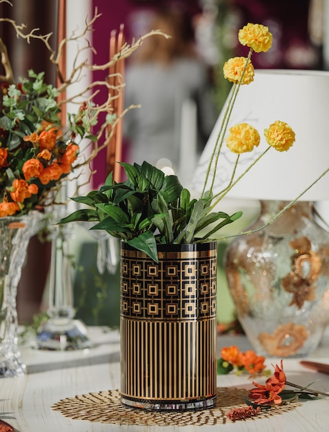 Vue latérale du vase de verre moderne avec pattenr géométrique avec des fleurs jaunes sur une table en bois