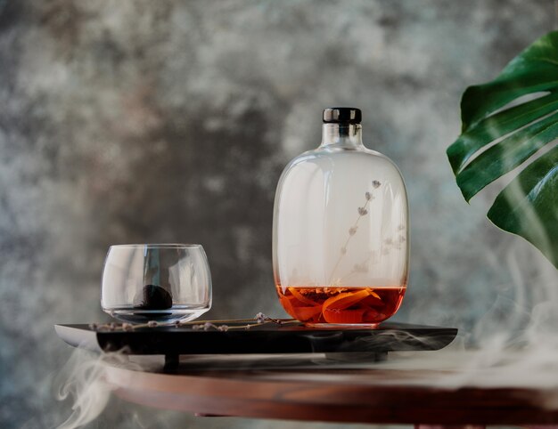 Vue latérale du vin chaud dans une bouteille décorative en verre sur une planche de bois