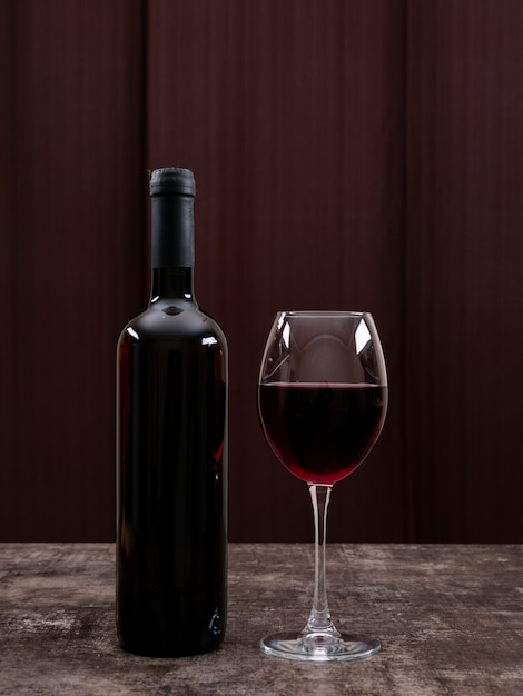 Vue latérale du vin rouge en bouteille avec verre sur vertical