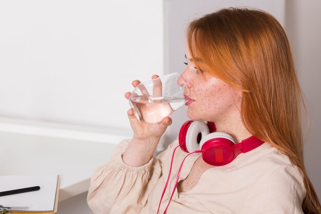 Vue latérale de l'eau potable des enseignantes pendant les cours en ligne