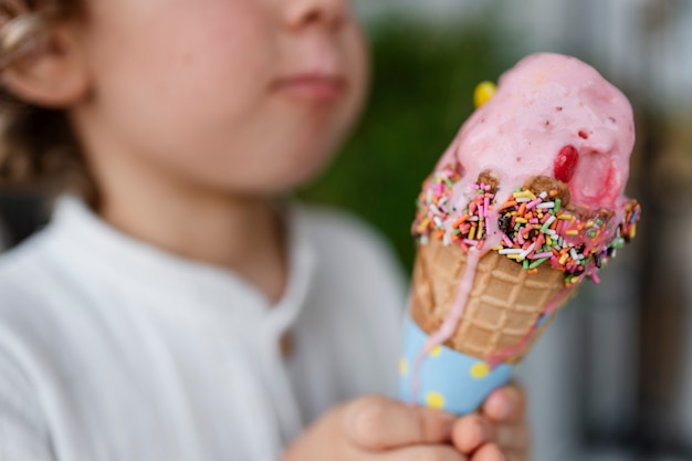 Vue latérale enfant flou tenant un cornet de crème glacée