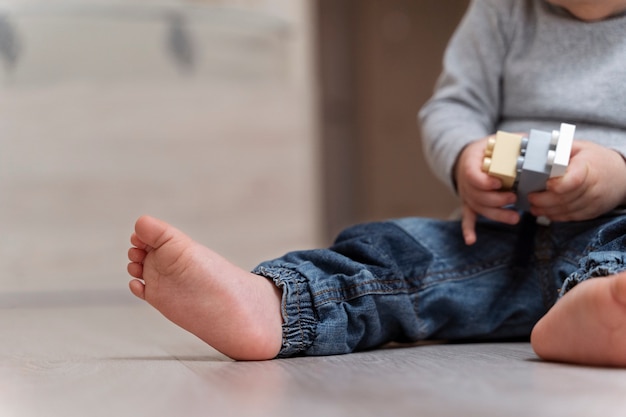 Photo gratuite vue latérale enfant mignon avec jouet sur le sol