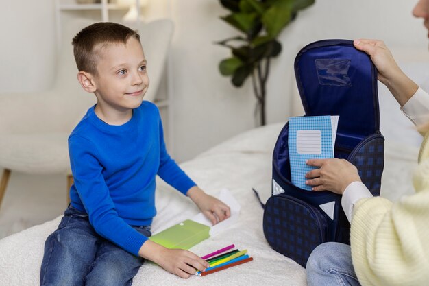 Vue latérale enfant préparant le sac à dos scolaire