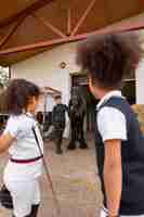 Photo gratuite vue latérale des enfants apprenant à monter à cheval