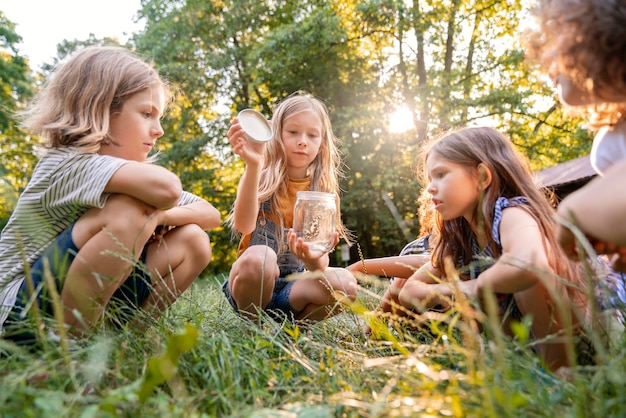 Vue latérale des enfants assis sur l'herbe