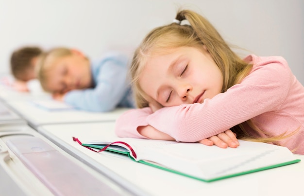 Photo gratuite vue latérale des enfants qui dorment sur leur bureau