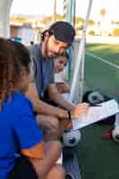 Photo gratuite vue latérale entraîneur de football enseignant aux enfants