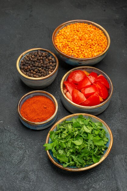 Vue latérale épices lentilles tomates herbes lentilles sur la table sombre