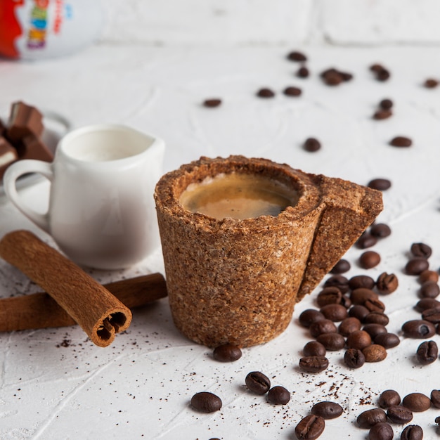 Photo gratuite vue latérale expresso dans une tasse en liège avec carafe avec du lait, de la cannelle, des grains de café