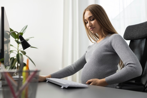 Vue latérale d'une femme d'affaires enceinte au bureau