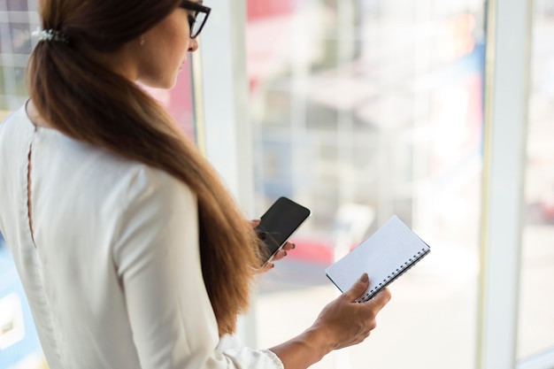 Vue latérale de la femme d'affaires avec smartphone et ordinateur portable