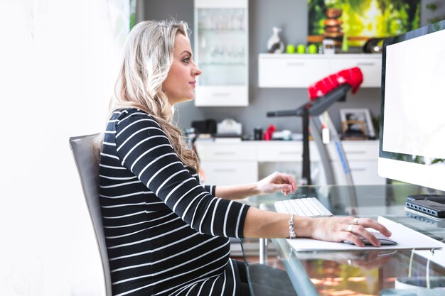 Vue latérale d&#39;une femme d&#39;affaires travaillant sur ordinateur