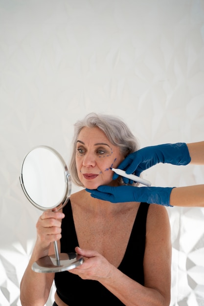 Vue latérale femme âgée regardant dans le miroir