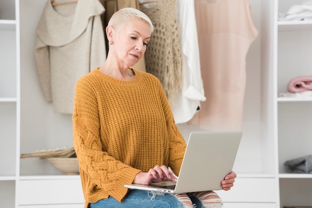 Vue latérale d'une femme âgée travaillant sur ordinateur portable