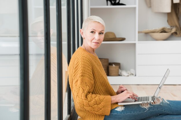 Vue latérale d'une femme âgée travaillant sur ordinateur portable