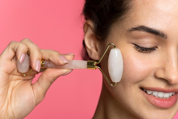 Photo gratuite vue latérale femme à l'aide d'un rouleau facial