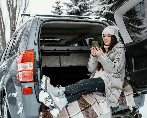 Vue latérale de la femme à l'aide de smartphone lors d'un voyage sur la route