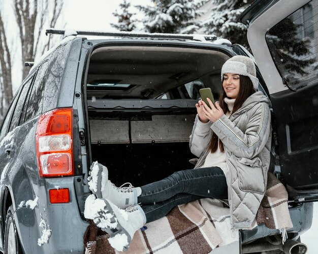 Vue latérale de la femme à l'aide de smartphone lors d'un voyage sur la route