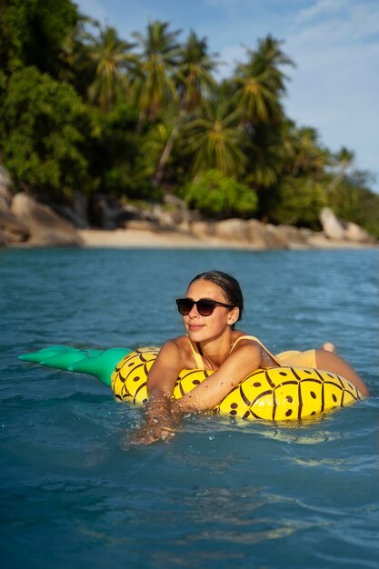 Vue latérale femme allongée sur un flotteur d'ananas