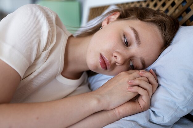 Vue latérale femme anxieuse allongée dans son lit