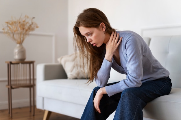 Vue latérale femme anxieuse assise sur un canapé