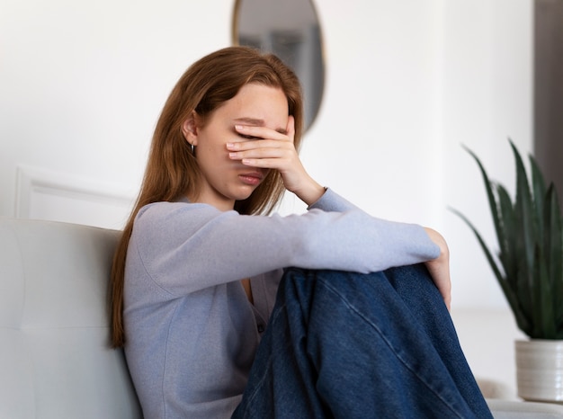 Photo gratuite vue latérale femme anxieuse assise sur un canapé