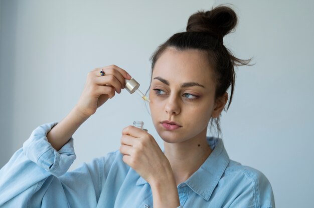 Vue latérale femme appliquant un traitement du visage