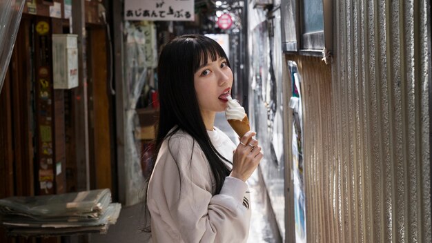 Vue latérale femme asiatique léchant le cornet de crème glacée