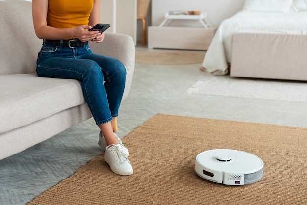 Vue latérale femme avec aspirateur robotique à la maison