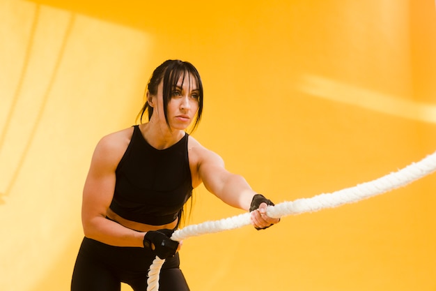 Vue latérale d'une femme athlétique en tenue de sport en tirant sur la corde