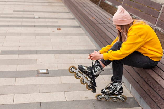 Vue latérale d'une femme attachant des cordes sur des patins à roues alignées