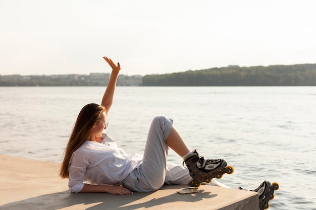 Vue latérale d'une femme au bord du lac portant des patins à roulettes