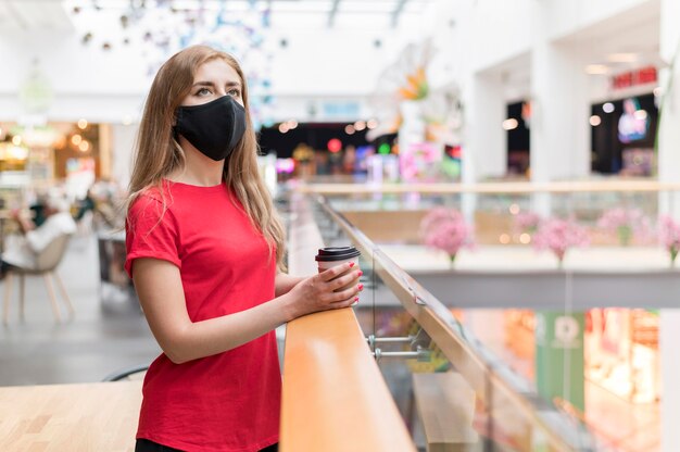 Vue latérale femme au centre commercial avec masque