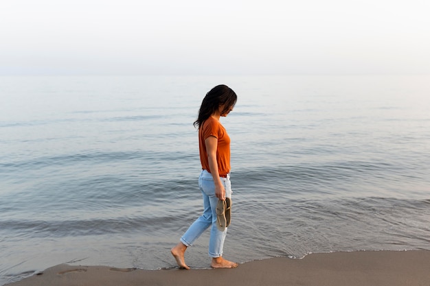 Vue latérale d'une femme bénéficiant d'une promenade au bord de la plage