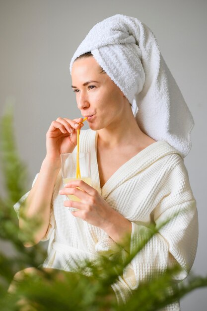 Vue latérale d'une femme bénéficiant d'un spa à la maison tout en buvant un verre