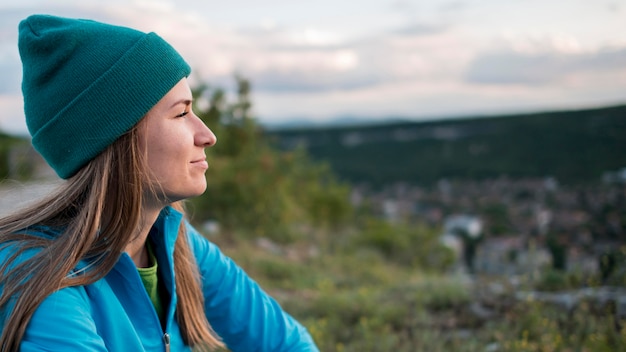 Vue latérale femme avec bonnet appréciant la vue