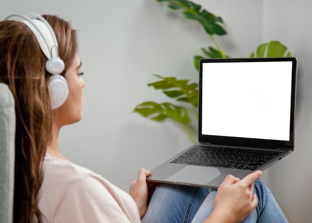 Vue latérale femme avec un casque à l'aide d'un ordinateur portable