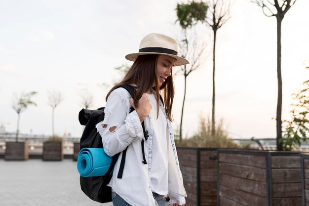 Vue latérale de la femme avec chapeau et sac à dos lors d'un voyage